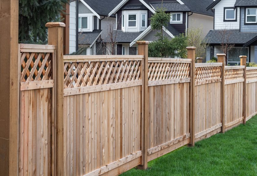 Row of new wood privacy fence panels with lattice tops in front of houses
